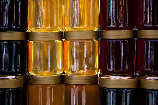 A group of honey jars, a close-up of a jar, and a jar of dark liquid, showcasing preserved food containers.